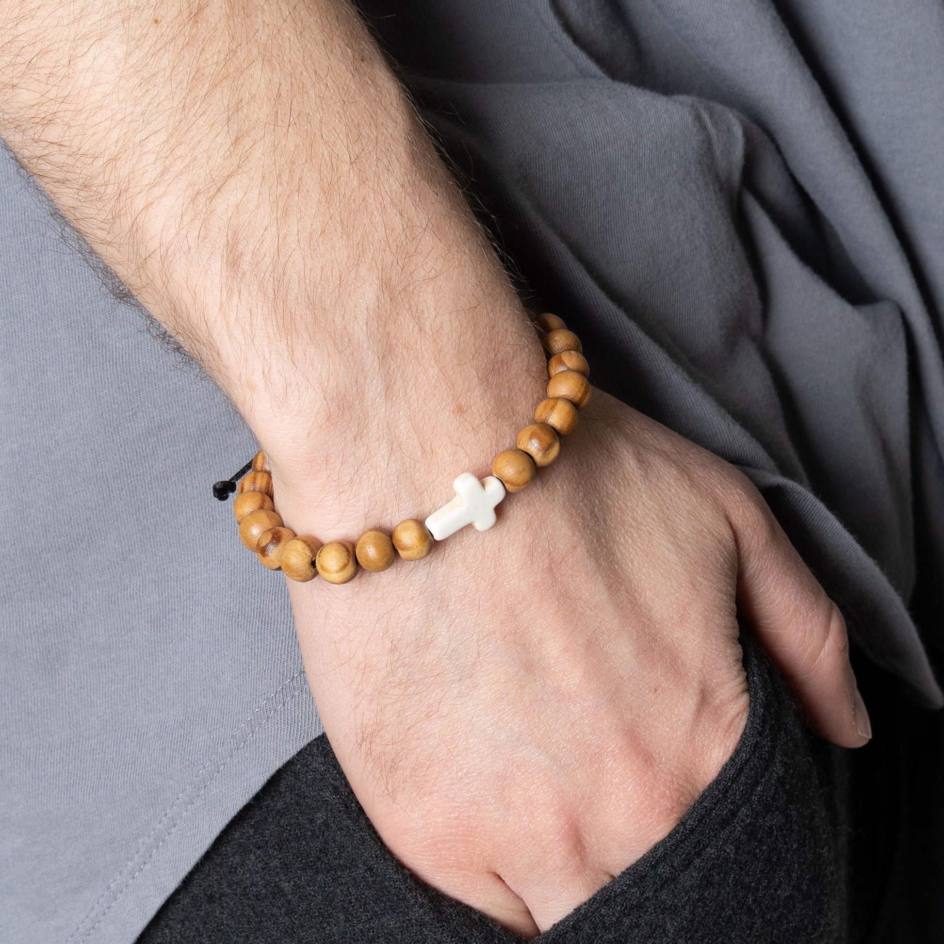 A man wearing a wooden beaded bracelet with white cross
