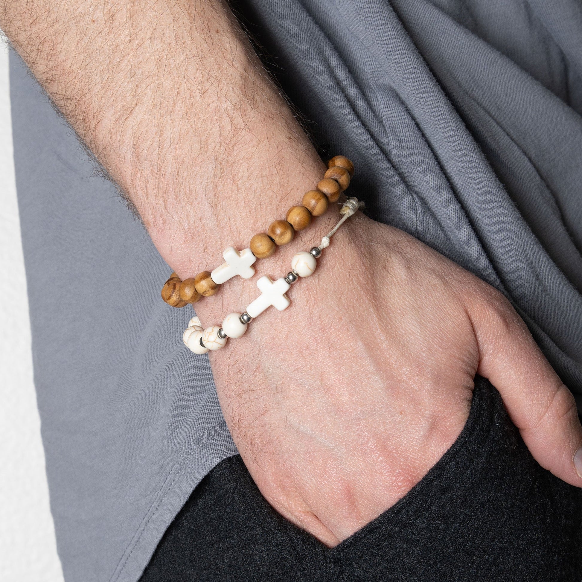 A man wearing a pair of beaded bracelets with white crosses