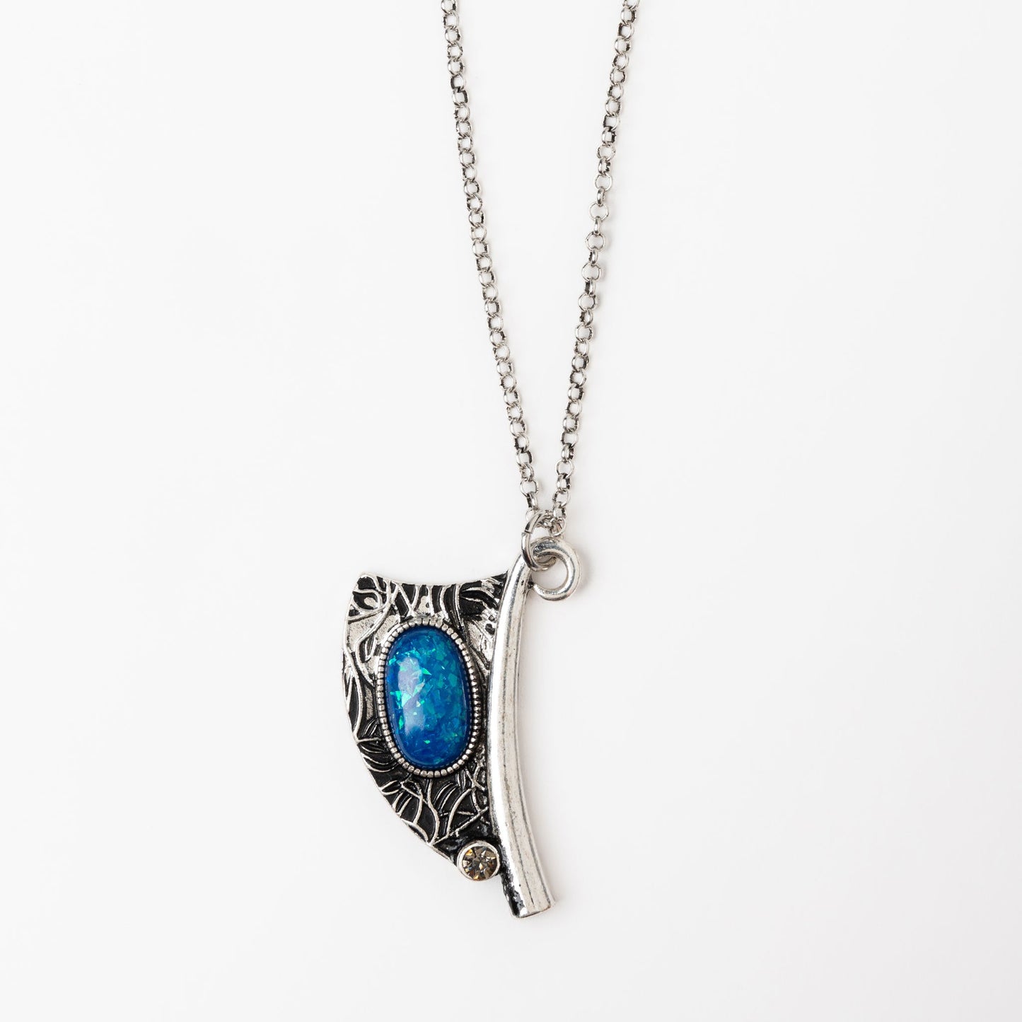 A silver pendant necklace with an intricate engraved design and a vibrant blue bead centered on the pendant