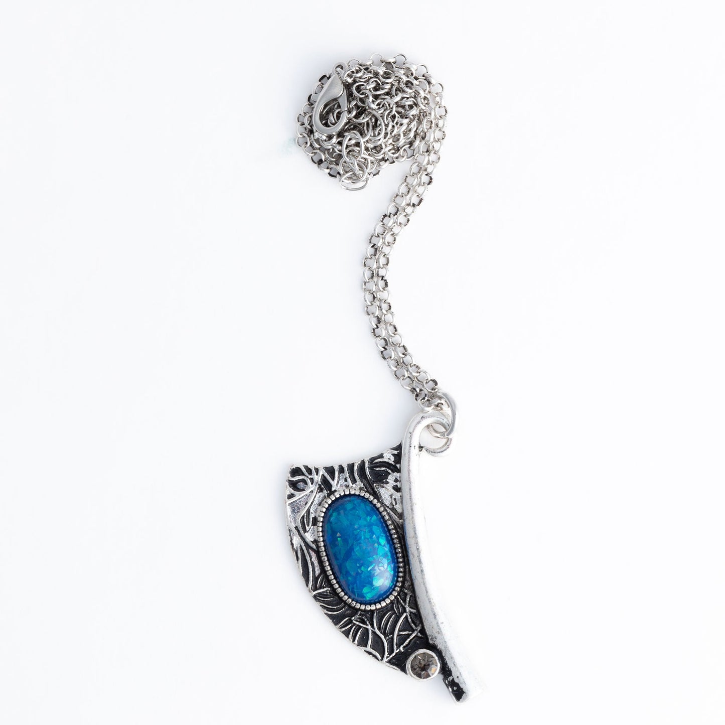 A silver pendant necklace with an intricate engraved design and a vibrant blue bead centered on the pendant
