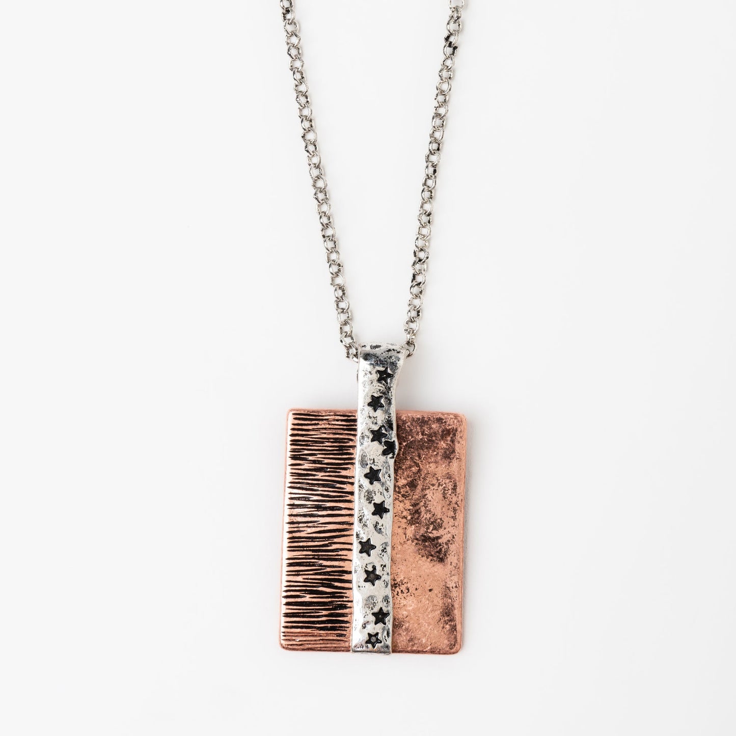 A pendant necklace with a two-toned copper and silver pendant featuring star engravings