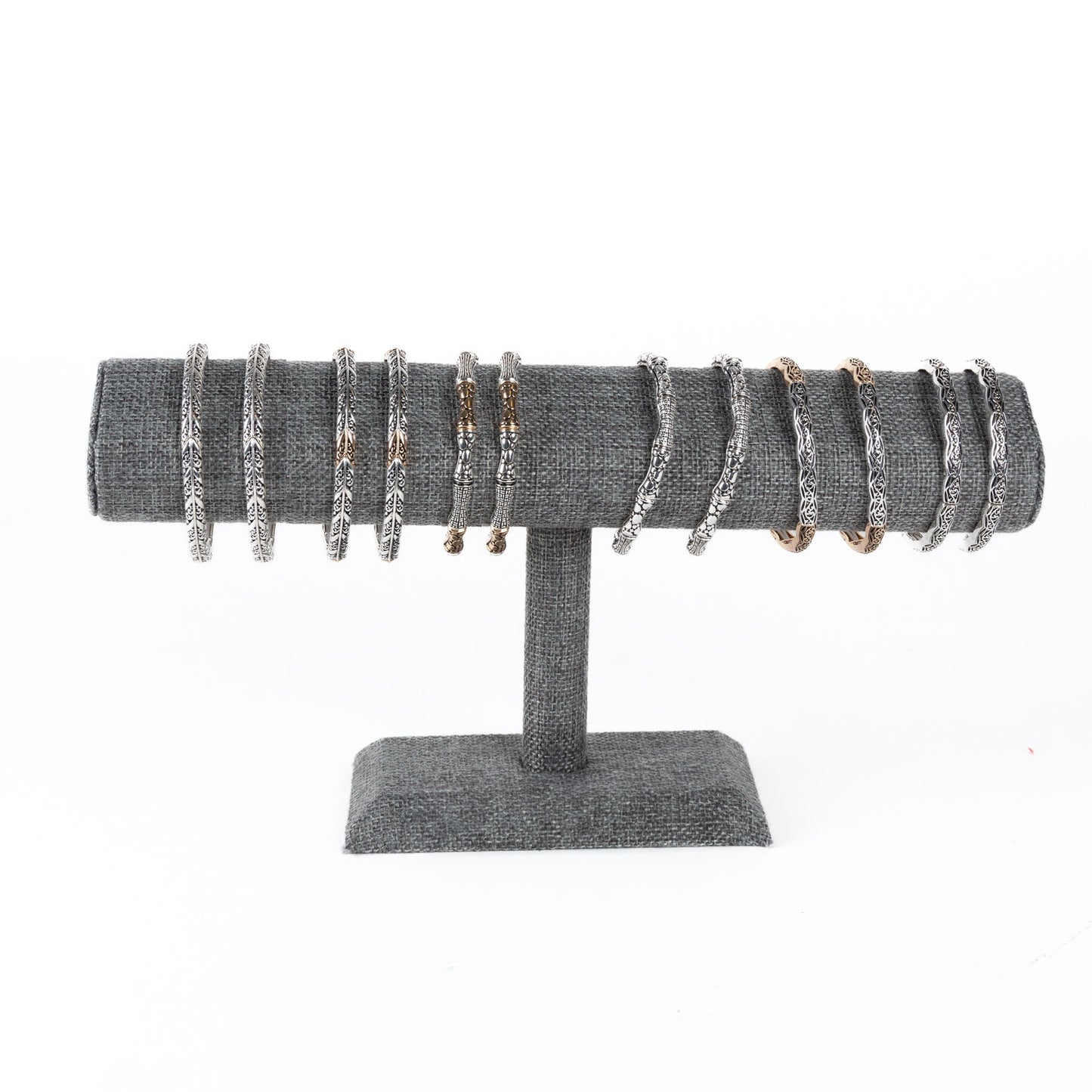 A collection of silver stretch bracelets displayed on a grey stand.