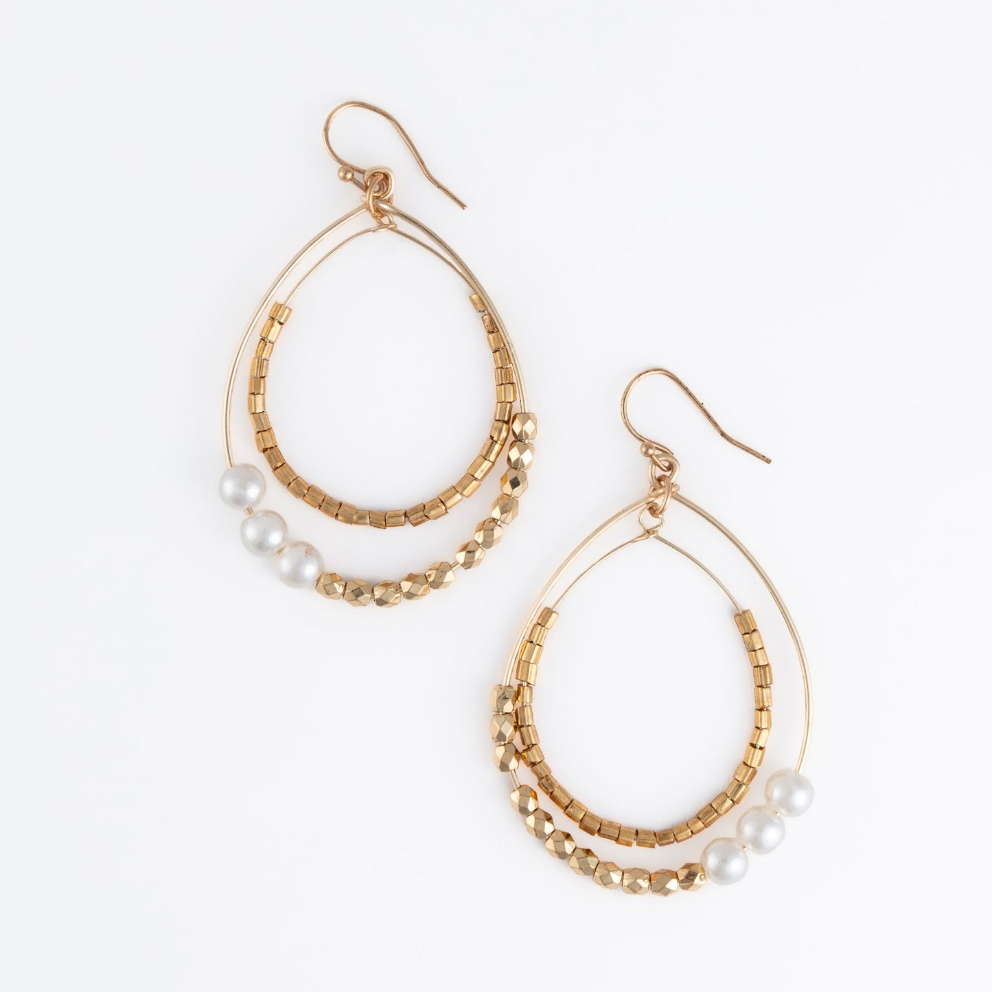 A pair of gold-colored hoop earrings with white pearl and golden bead embellishments