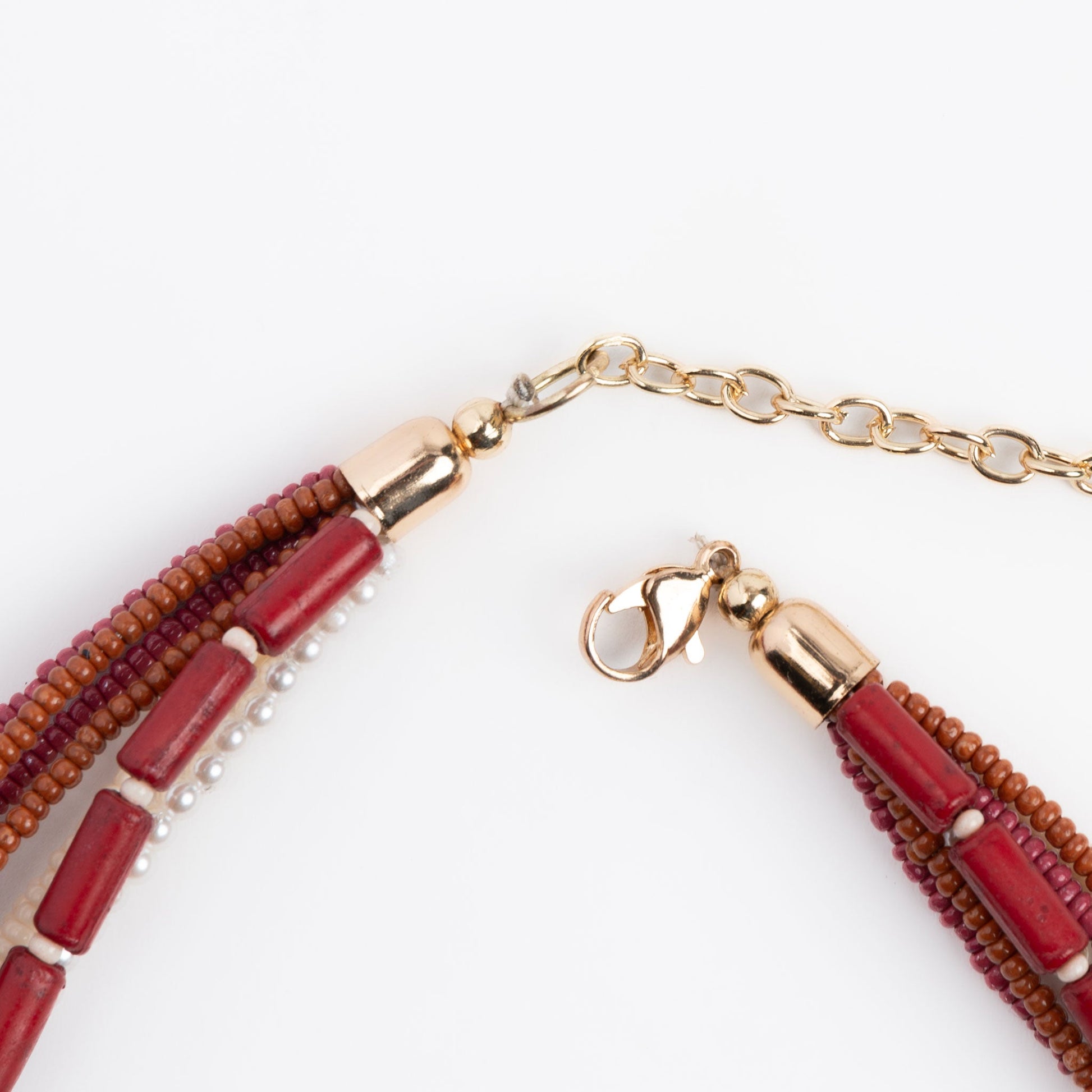 A seed bead necklace in red and gold colors with a gold lobster clasp closure