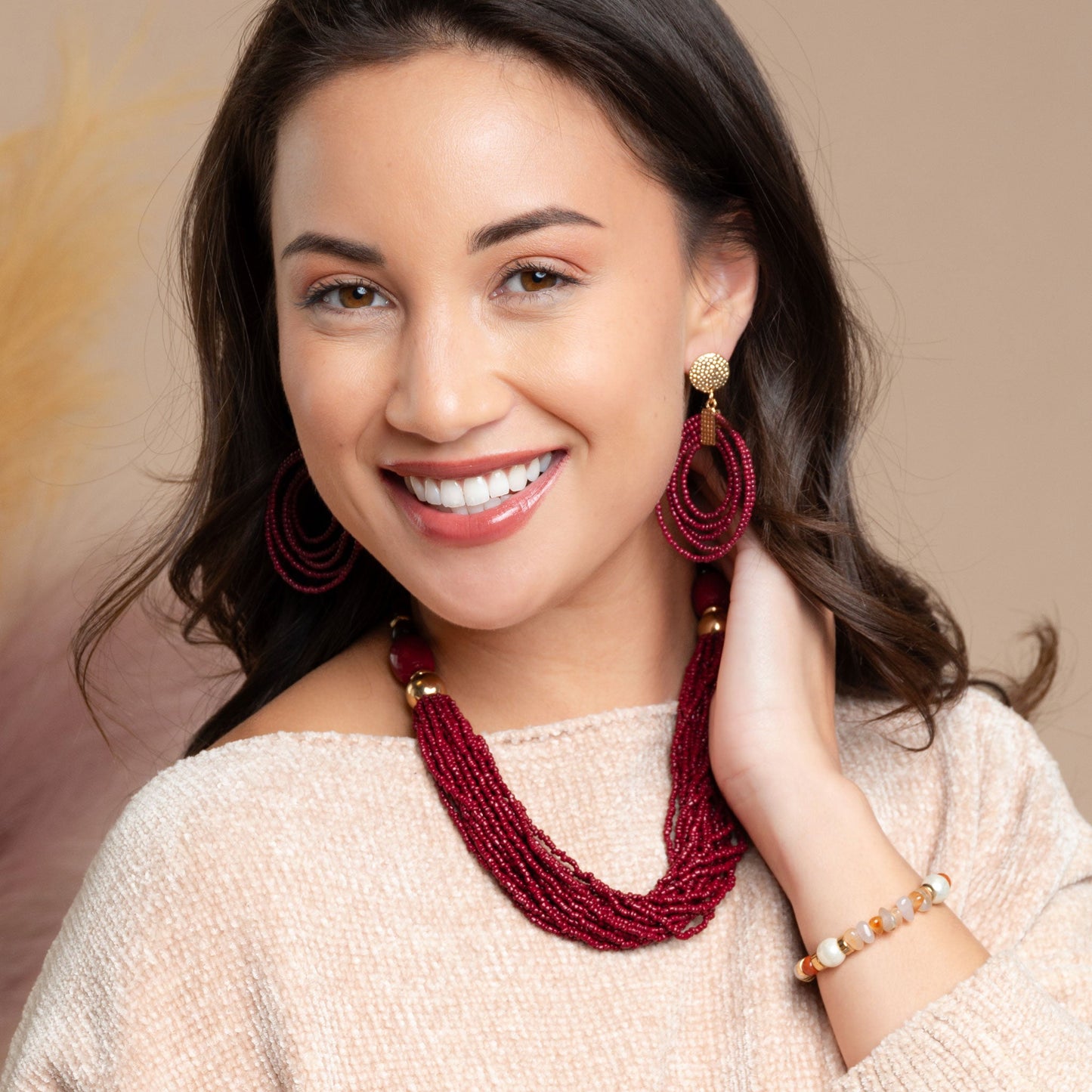 A woman wearing a pair of red seed bead earrings with a coordinating red seed bead necklace