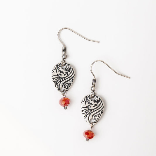 A pair of silver paisley design earrings with red glass bead accents, displayed against a white background.