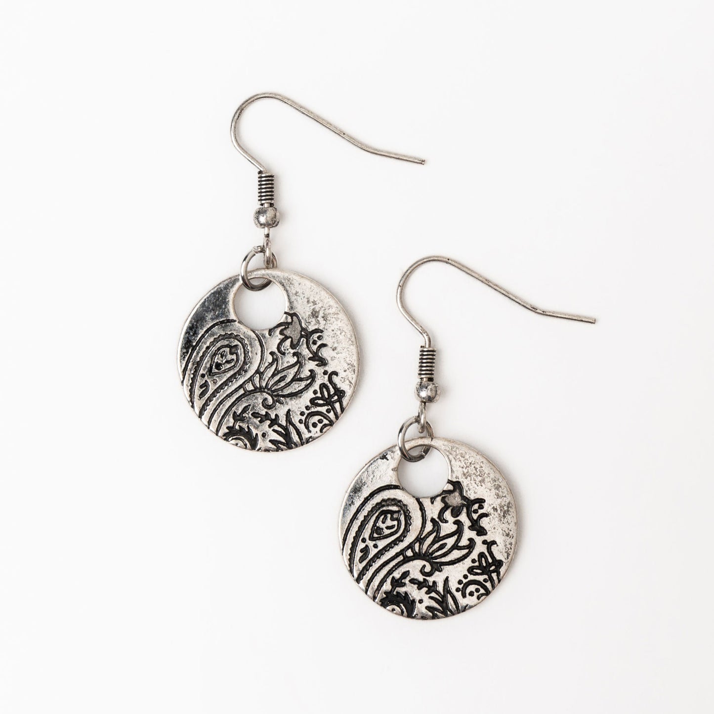 A pair of silver mandala-shaped earrings with paisley design, dangled from fishhook closures.