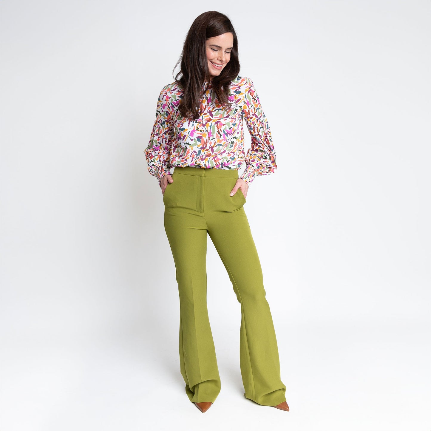 A woman wearing a multicolored balloon sleeve blouse with a round neckline, paired with green bell bottom trousers