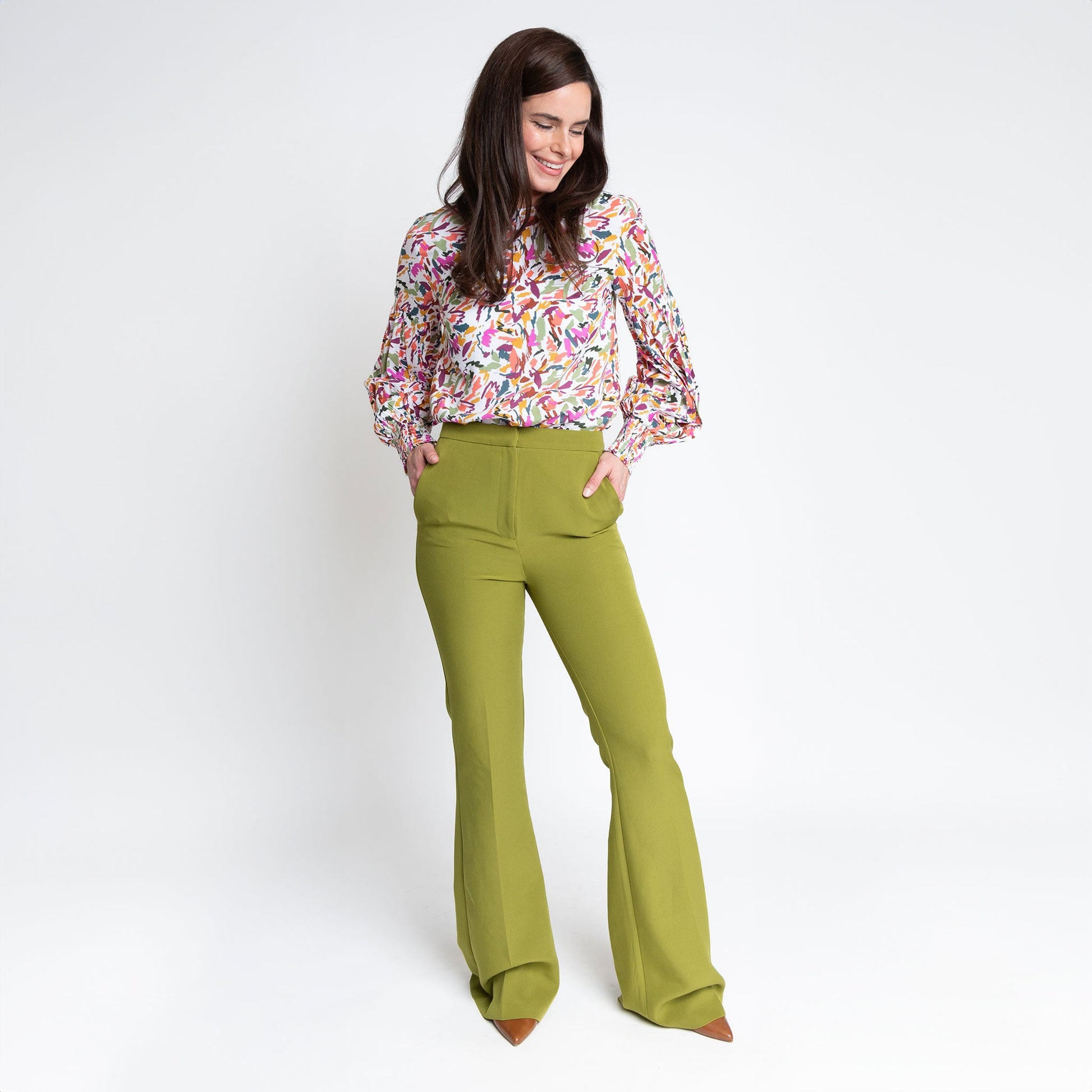 A woman wearing a multicolored balloon sleeve blouse with a round neckline, paired with green bell bottom trousers