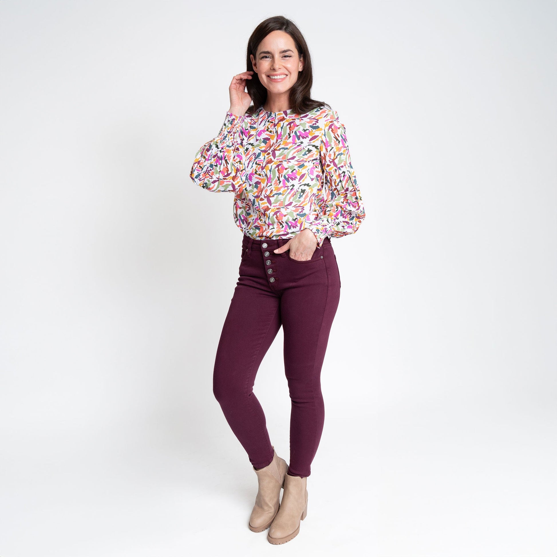A woman wearing a multicolored balloon sleeve blouse with a round neckline, paired with purple trousers
