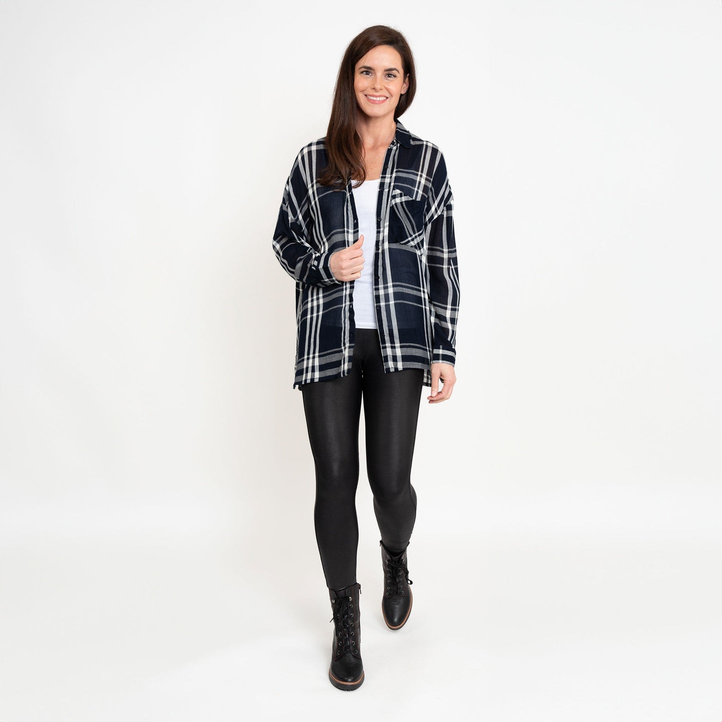 A woman wearing a navy plaid button-up shirt with button-up design and a relaxed fit, paired with black leather leggings