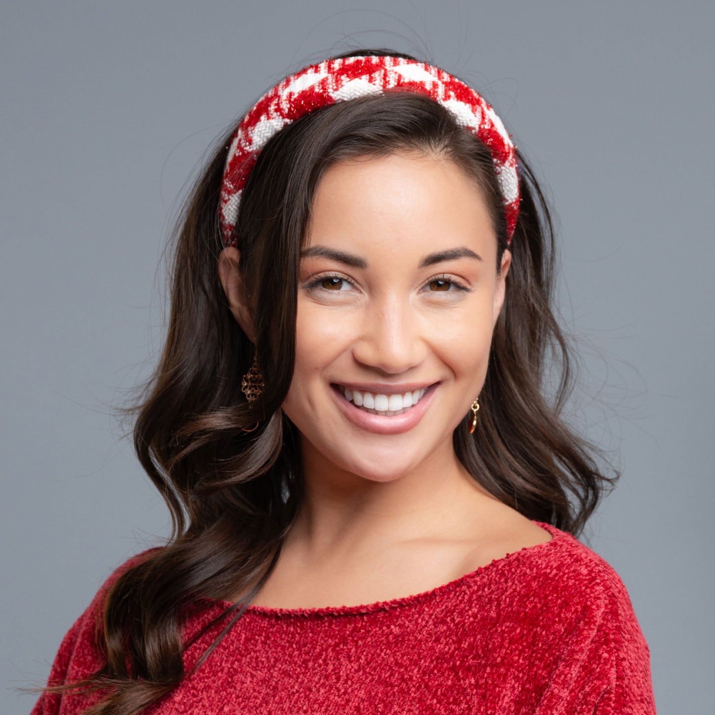 A woman wearing a red and white checkered boucle headband and a red chenille top.