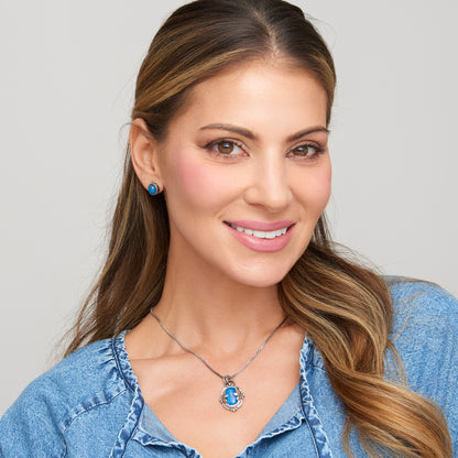 Woman wearing a blue pendant necklace and earrings against a gray background